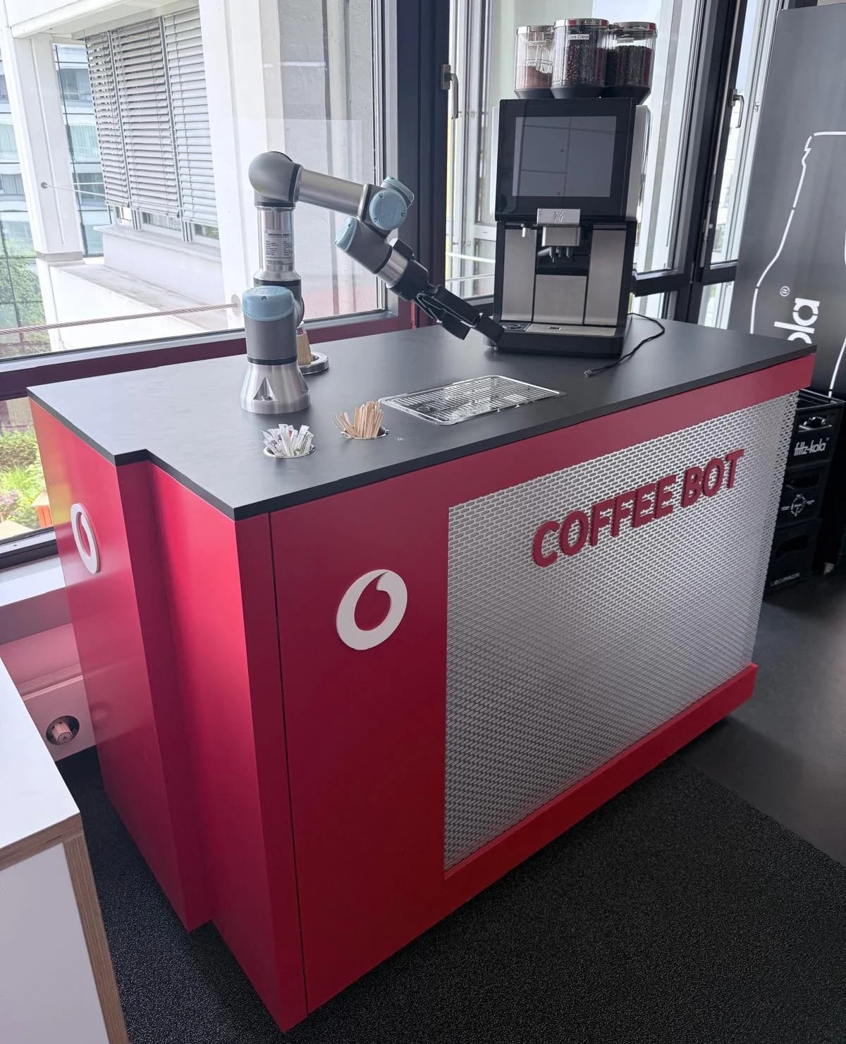 Coffee Bot mit Roboterarm und Kaffeemaschine auf einer rechteckigen Station.